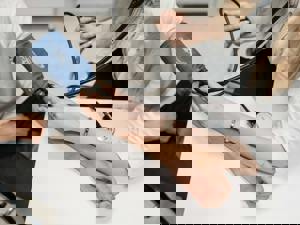 A healthcare professional measures a patient's blood pressure using a blue cuff and stethoscope. 